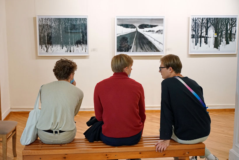 Трое молодых людей сидят перед тремя картинами